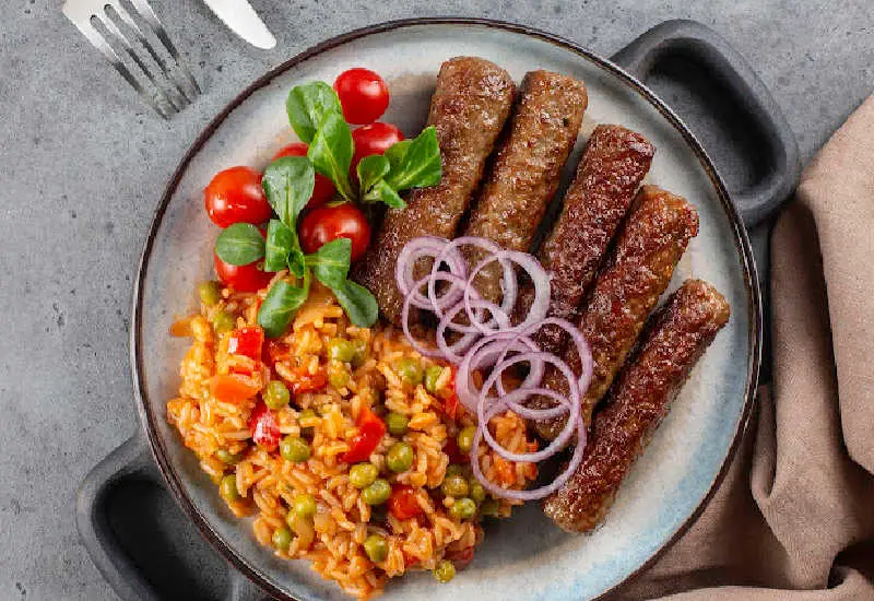 A top down image of cooked cevapi and djuvec